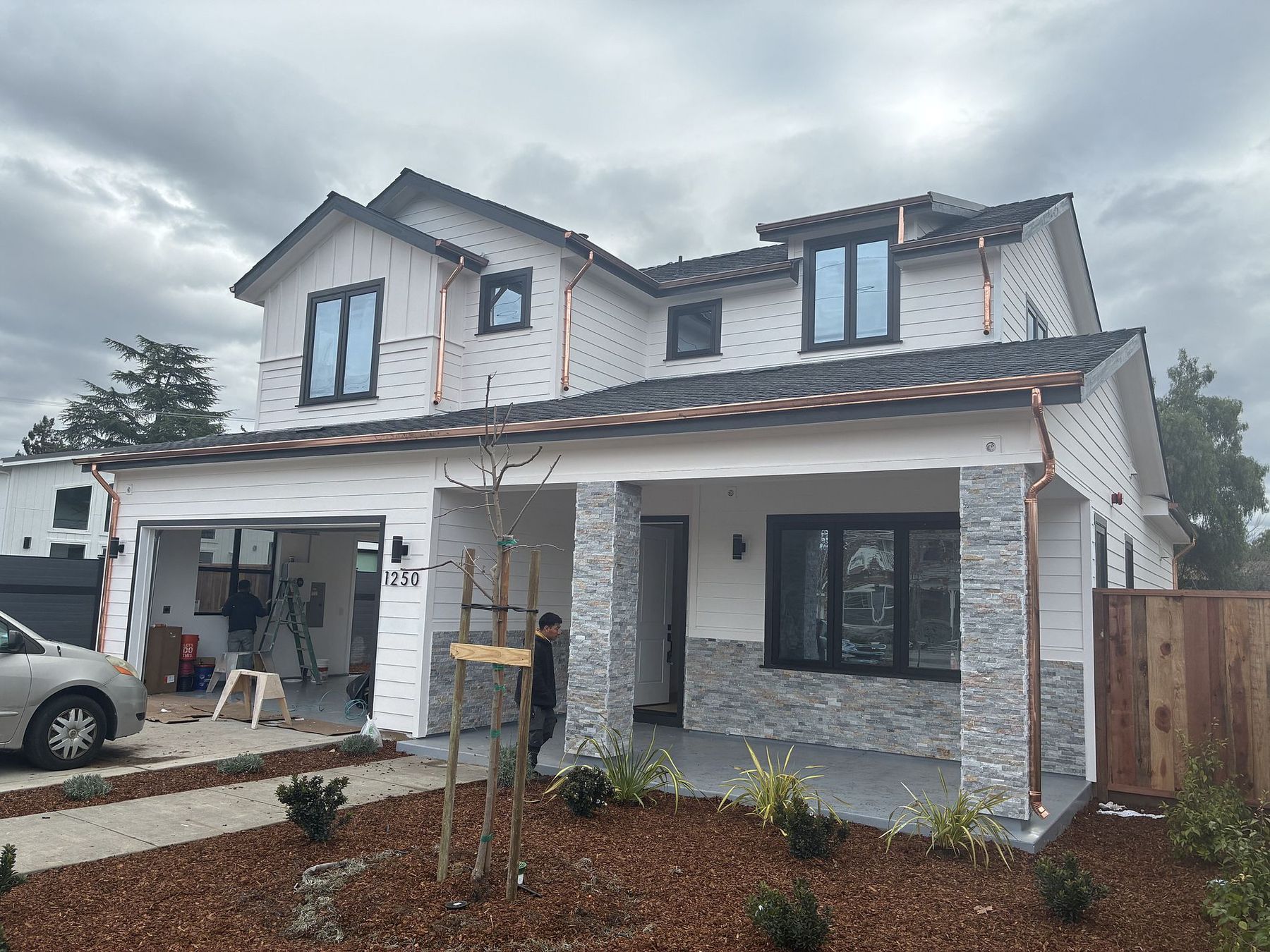 Freshly installed half-round copper gutters and round copper downspouts on a new-construction modern farmhouse home in the Bay Area by Keith Roofing Company