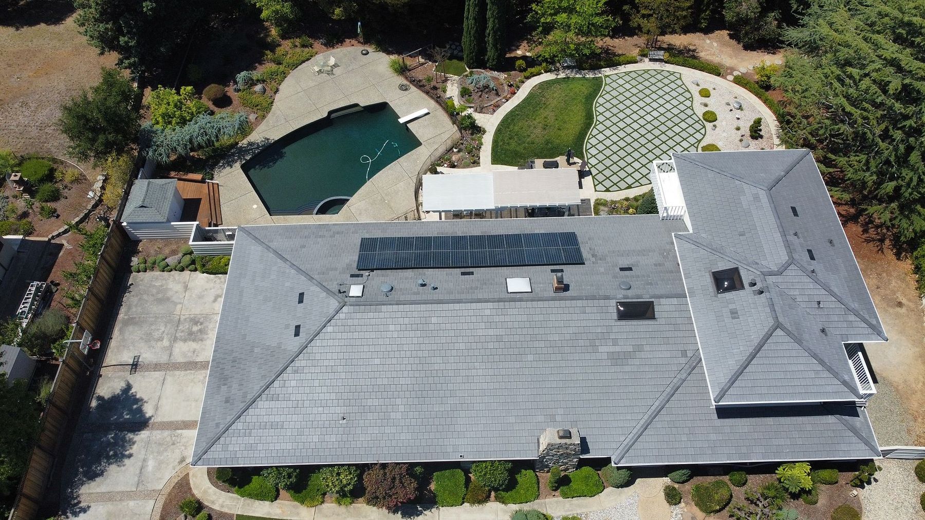 Aerial view of a finished tile roof on a high-end Bay Area residential property by Keith Roofing Company — flat profile tile, complex hipped geometry, integrated solar array